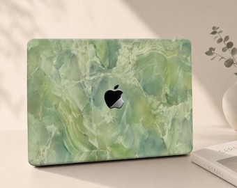 Puede incluir: Una funda para portátil con un patrón de piedra veteada en tonos verde claro y blanco con acabado brillante. El diseño cubre la tapa rectangular del dispositivo, dejando visible el logotipo negro de Apple en el centro de la superficie.