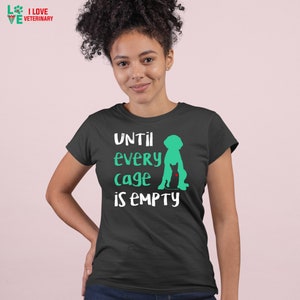 May include: A black t-shirt with a white graphic of a dog and cat silhouette. The text "UNTIL EVERY CAGE IS EMPTY" is printed in white on the shirt.