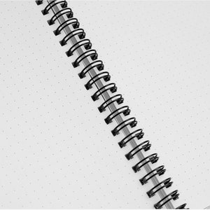 a black and white spiral notebook on a white surface