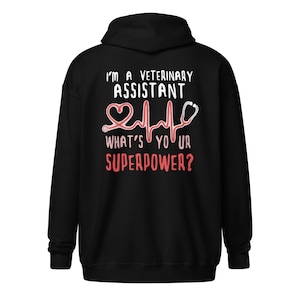 Peut inclure: Sweat-shirt à capuche noir avec le texte "I'm a Veterinary Assistant What's Your Superpower?" en blanc avec un cœur rouge et un graphique de stéthoscope.