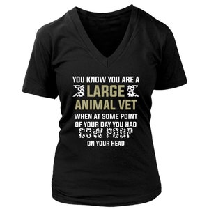 May include: Black V-neck t-shirt with the text "YOU KNOW YOU ARE A LARGE ANIMAL VET WHEN AT SOME POINT OF YOUR DAY YOU HAD COW POOP ON YOUR HEAD".
