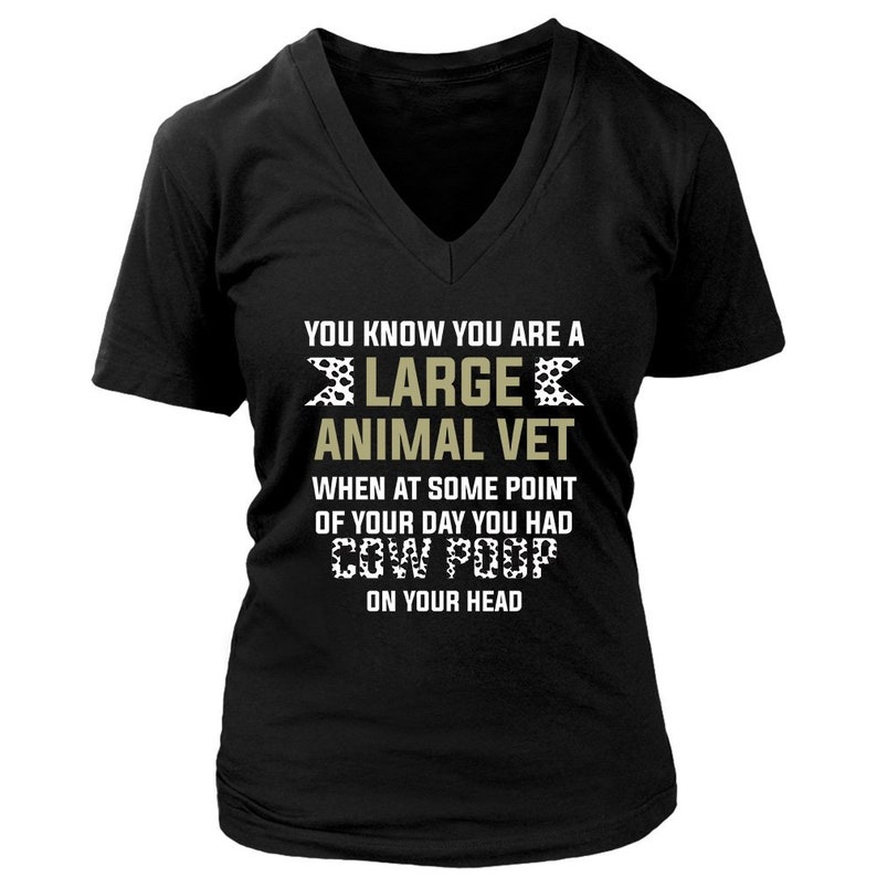 May include: Black V-neck t-shirt with the text "YOU KNOW YOU ARE A LARGE ANIMAL VET WHEN AT SOME POINT OF YOUR DAY YOU HAD COW POOP ON YOUR HEAD".