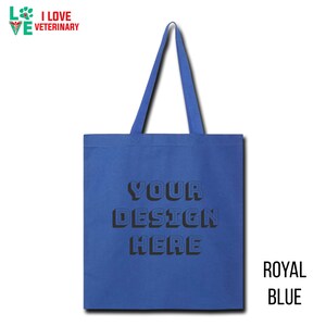 Op de afbeelding: Een koninklijk blauwe tote bag met de tekst "YOUR DESIGN HERE" in zwart. De tas heeft een 3D-effect op de tekst.