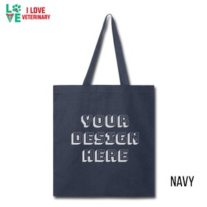 Op de afbeelding: Een donkerblauwe tote bag met witte tekst die "YOUR DESIGN HERE" zegt.