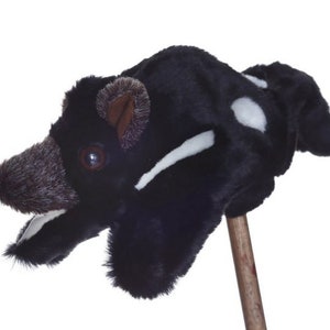 May include: Black and white plush puppet of a Tasmanian devil with a brown nose and white markings. The puppet is attached to a wooden stick.