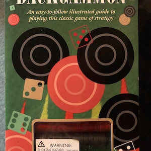 Puede incluir: Caja de juego de Backgammon con fondo verde y el título "BACKGAMMON" en letras blancas grandes. La caja incluye dados, fichas y una advertencia sobre piezas pequeñas. La caja también incluye un libro de 64 páginas.
