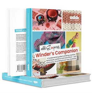 May include: A book titled "addiExpress Winder's Companion" with a blue cover, showcasing knitting machine techniques. The cover features images of knitting projects, yarn, and the Addi Express logo. The book is a guide to knitting machine techniques.
