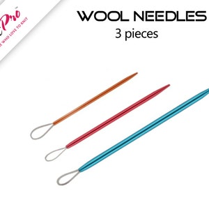 May include: Three knitting needles, one copper, one red, and one blue, with a loop at the end of each needle. The needles are arranged in a row, with the copper needle at the top, the red needle in the middle, and the blue needle at the bottom. The text "WOOL NEEDLES 3 pieces" is printed above the needles.