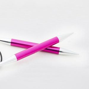 May include: Two crossed knitting needles with bright pink shafts and silver tips. The needles have a metallic sheen and are set against a white background. The tips are white and pointed, designed for yarn manipulation.