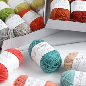 May include: A variety of colorful yarn balls in different shades of orange, red, green, blue, and pink. The yarn is labeled "Scheepjes Metropolis" and "Scheepjes".