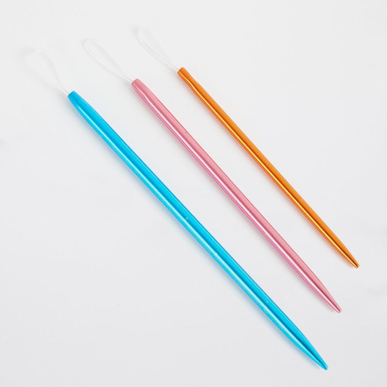 May include: Three knitting needles, one blue, one pink, and one orange, with white loops at the top.