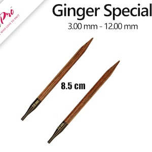 Op de afbeelding: Twee houten breinaalden, een van 8,5 cm lang en de andere van 7,5 cm lang. De naalden zijn bruin met een donkerbruine streep die over de hele lengte van elke naald loopt. De naalden zijn geëtiketteerd met "Knit Pro" en "Ginger Special 3,00 mm - 12,00 mm".