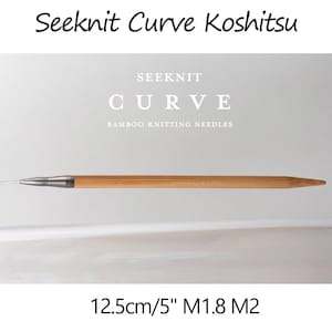 May include: A Seeknit Curve Koshitsu bamboo knitting needle with a metallic joint and a thin cord attached. The text reads Seeknit Curve Koshitsu, SEEKNIT CURVE BAMBOO KNITTING NEEDLES, and 12.5cm/5" M1.8 M2. The needle is light brown wood.