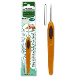 Könnte beinhalten: Ein ergonomischer Häkelhaken aus Stahl mit Soft-Touch-Griff in Senfgelb. Der Haken hat einen dunkelbraunen ovalen Griff und einen silbernen Metallhaken. Die Verpackung enthält den Text "Soft Touch Steel Crochet Hook" und "Easy & Ergonomic Crocheting."