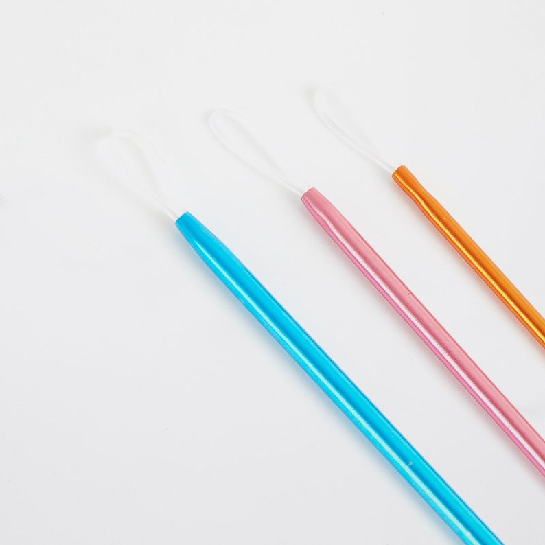 May include: Three crochet hooks with white loops at the end. The hooks are blue, pink, and orange.