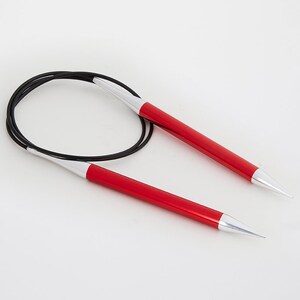 May include: A pair of red and silver circular knitting needles. The needles have a vibrant red shaft with silver tips and are connected by a black flexible cable. The needles are designed for knitting projects.