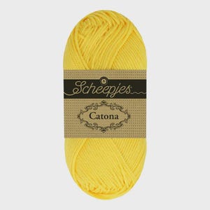 May include: A bright yellow skein of Scheepjes Catona cotton yarn. The yarn is wrapped with a brown label featuring the brand name and the yarn name, Catona, in an ornate font. The yarn is tightly wound and ready for crafting.