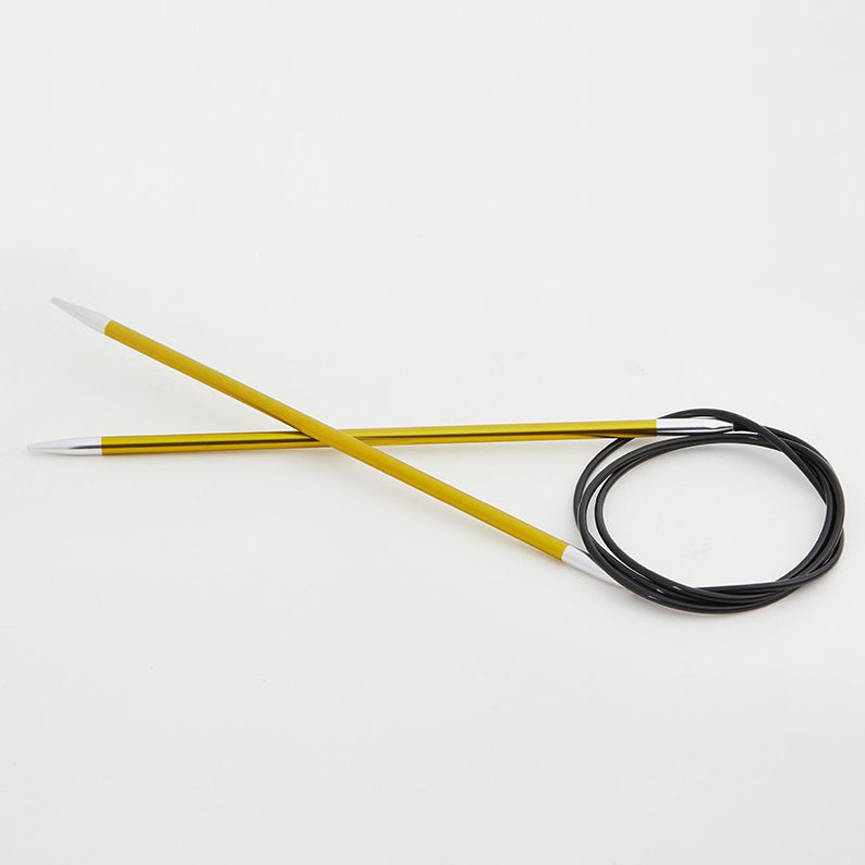 May include: A pair of yellow circular knitting needles with white tips and a black flexible cable. The needles are made of metal and are designed for knitting projects. The needles are shown against a white background.