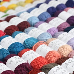 May include: A close-up view of a variety of colorful yarn balls, each labeled with the brand name "Scheepjes" and the yarn type "Metropolis".
