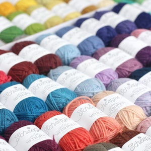 May include: A close-up of a variety of colorful yarn balls, each labeled with the brand name "Scheepjes" and the yarn line "Metropolitan".