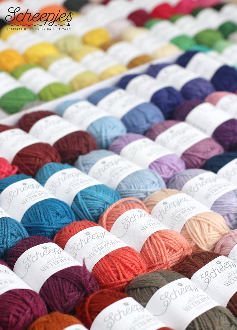 May include: A close-up of a variety of colorful yarn balls, each labeled with the brand name "Scheepjes" and the yarn line "Metropolitan".