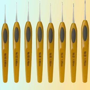 Op de afbeelding: Een set van acht haaknaalden met gele handvatten en zilveren metalen punten. Elke haaknaald is gemarkeerd met een nummer en de grootte in millimeters, variërend van 0,50 mm tot 1,75 mm. De handvatten hebben een zwarte ovale grip.