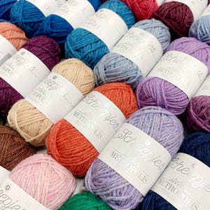 May include: A collection of colorful yarn skeins with the text "Scheepjes" and "with love from Metropolis" on the labels.