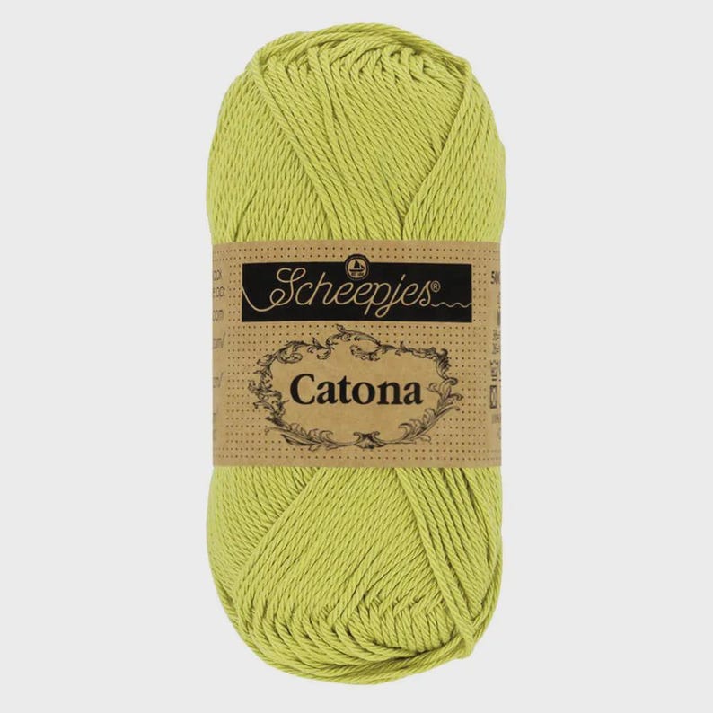 May include: A skein of light green Scheepjes Catona cotton yarn. The yarn is wrapped with a brown label featuring the brand name and product name. The yarn is a solid, vibrant green color.