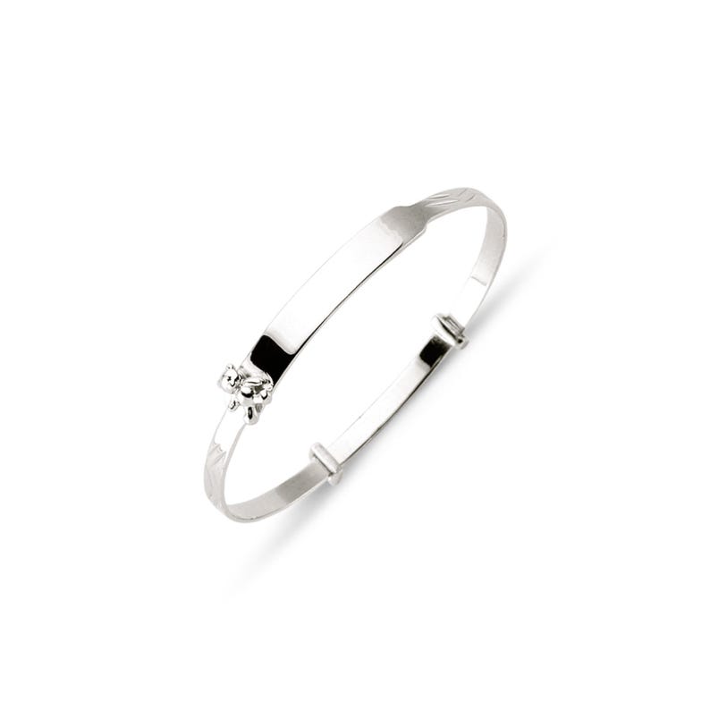 May include: A silver adjustable baby bracelet with a small floral design. The bracelet has a smooth, rectangular plate for engraving and a clasp for adjusting the size. The bracelet is made of shiny, polished metal.