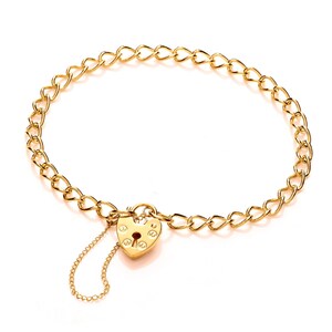 May include: A gold chain bracelet with a heart-shaped padlock charm. The charm has a keyhole and a detailed design.