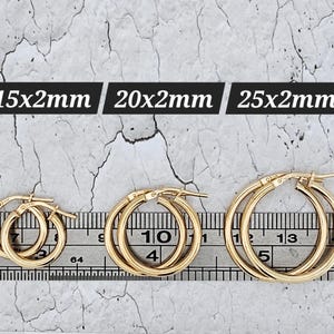 Könnte beinhalten: Drei Paar goldene Creolen in verschiedenen Größen: 15x2mm, 20x2mm und 25x2mm. Die Ohrringe werden auf einem Lineal präsentiert, das ihre Abmessungen zeigt. Der Text "15x2mm", "20x2mm" und "25x2mm" wird über den Ohrringen angezeigt.