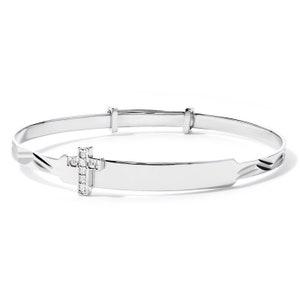 May include: A silver-toned adjustable bangle bracelet. The bracelet features a rectangular nameplate and a cross charm adorned with small, clear gemstones. The design is simple and elegant, suitable for a religious occasion.