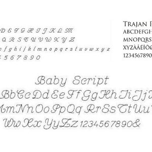 May include: A white background displays three different font styles: Vanessa, Trajan Pro, and Baby Script. Each font shows the alphabet, both uppercase and lowercase, along with numbers and special characters. The Baby Script font is a cursive style.