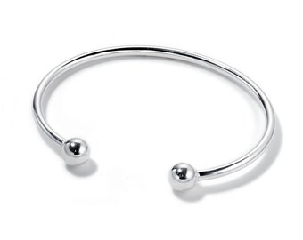Op de afbeelding: Een zilveren armband met twee ronde ballen aan de uiteinden.
