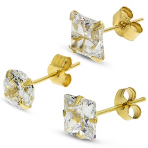 Puede incluir: Un par de pendientes de oro con piedras de circonita cúbica cuadradas transparentes. Los pendientes tienen un poste y una mariposa en la parte posterior.