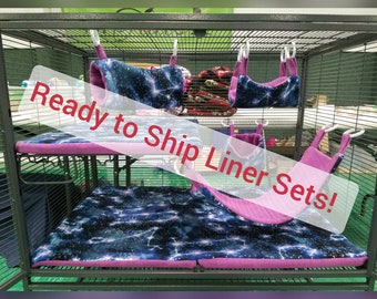 May include: A cage liner set with a galaxy print and pink trim. The set includes a hammock, a tunnel, and a bottom liner. The cage liner set is ready to ship.