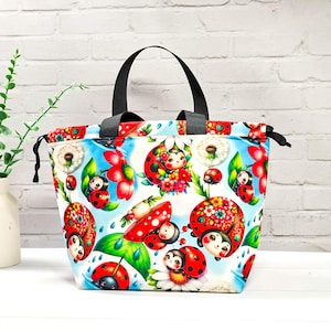 Könnte beinhalten: Eine weiße Keramik-Tasse mit schwarzem Henkel und dem Text "But First, Coffee" in schwarzer, handschriftlicher Schrift. Die Tasse steht auf einer weißen Oberfläche.