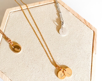 May include: Two gold necklaces with initial charms. One necklace has a single charm with the letter L, the other has two charms with the letter L.