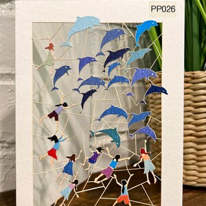 Carte artistique découpée au laser représentant des dauphins et des personnages