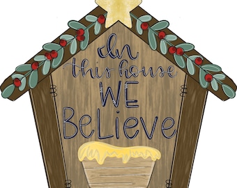 May include: A wooden Christmas sign shaped like a manger with a star on top. The sign says "In this house we believe".