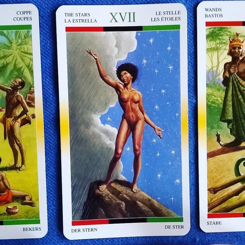 Puede incluir: La carta del tarot La Estrella presenta a una mujer desnuda de pie sobre una roca con los brazos extendidos. El fondo es un cielo azul con nubes blancas y estrellas. El n&uacute;mero de la carta XVII est&aacute; en la parte superior central de la carta. El t&iacute;tulo de la carta es "The Stars" en ingl&eacute;s, "La Estrella" en espa&ntilde;ol, "Le Stelle" en italiano, "Les &Eacute;toiles" en franc&eacute;s, "Der Stern" en alem&aacute;n, "De Ster" en holand&eacute;s y "The Stars" en japon&eacute;s.