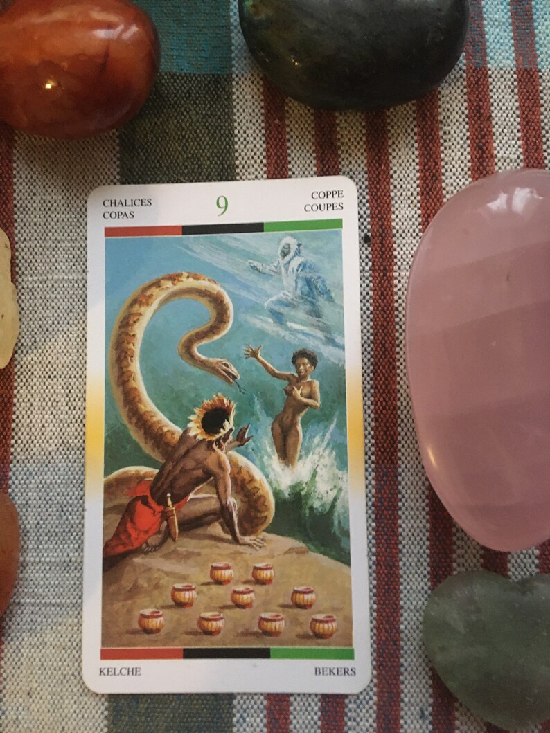 Puede incluir: Carta de tarot que representa el Nueve de Copas, tambi&eacute;n conocido como el Nueve de Copas. La carta muestra a un hombre con un tocado de pie cerca de una serpiente, una mujer en el agua y nueve copas doradas en el suelo. La carta est&aacute; titulada "Chalices, Copas, Kelche, Bekers, Coppe, Coupes".