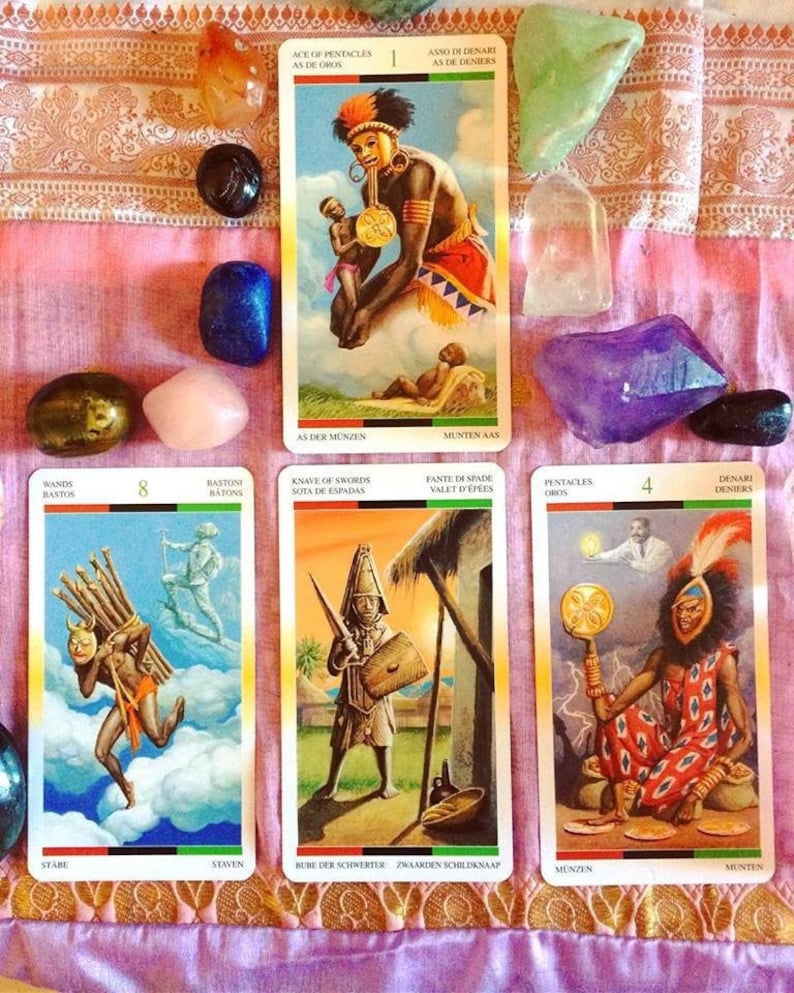 Puede incluir: Cartas de tarot extendidas sobre una tela de patr&oacute;n rosa y dorado. Las cartas son de la baraja 'African Tarot' y presentan ilustraciones de personas de color. Las cartas son: 8 de Bastos, Caballo de Espadas, 4 de Pent&aacute;culos y As de Pent&aacute;culos.
