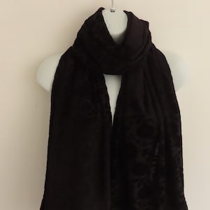 May include: A black velvet scarf with a subtle floral pattern. The scarf is draped over a mannequin.