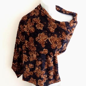 May include: A dark navy blue scarf featuring a repeating pattern of copper-brown roses. The fabric has a subtle sheen and is draped over a white mannequin, showcasing the floral design across the entire surface of the rectangular accessory.