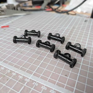 May include: A white ceramic mug with a black handle and the text "But First, Coffee" in a black, handwritten-style font. The mug is on a white surface.