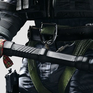 May include: A black sledgehammer with a long black handle. The handle has a red and black plaid ribbon tied around it.