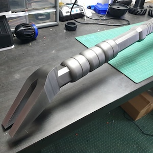 May include: A silver metal pry bar with a textured grip and a curved, forked end.