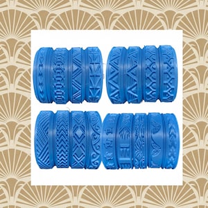 May include: Eight blue textured rolling pins with various patterns, including hearts, geometric shapes, and floral designs. The rolling pins are arranged in two rows of four, showcasing the different embossed textures.