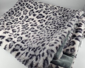 May include: A soft, plush throw blanket with a gray and white leopard print. The blanket is folded and has a gray underside.